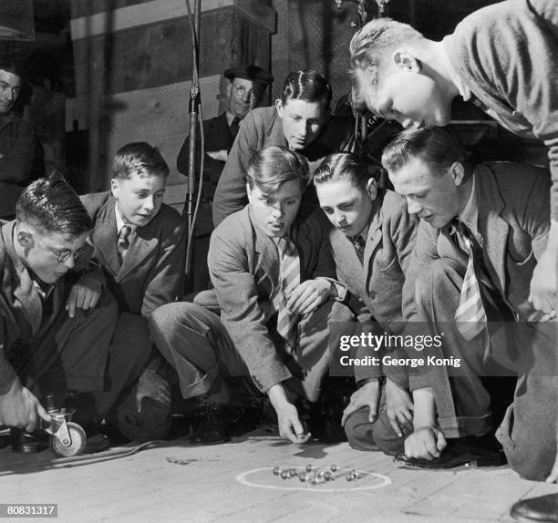 Film director Richard Attenborough playing marbles with some of the cast during a break from filming 'The Guinea Pig' at Elstree Studios, April 1948.