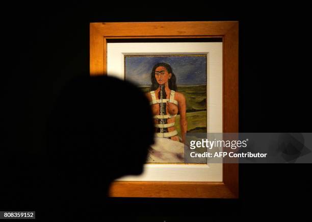 Woman walks by the painting "The broken column" by Mexican artist Frida Kahlo, during a tour for journalists prior to the opening of the exhibition...