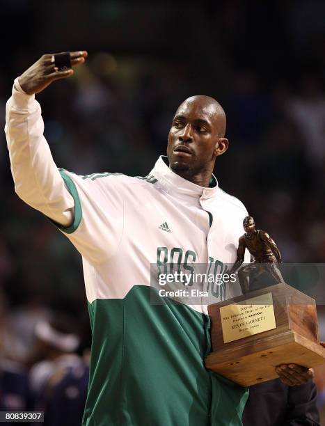 Kevin Garnett of the Boston Celtics signals for his teammates to join him as he accepts the NBA's Defensive Player of the Year Award before the game...