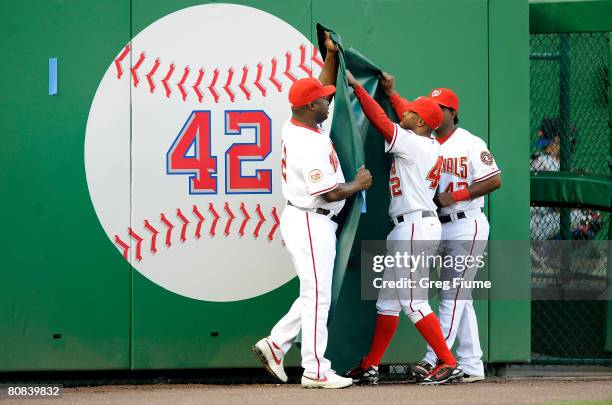 Ray King, Lastings Milledge and Willie Harris of the Washington Nationals unveil Jackie Robinson's number before their game against the New York Mets...