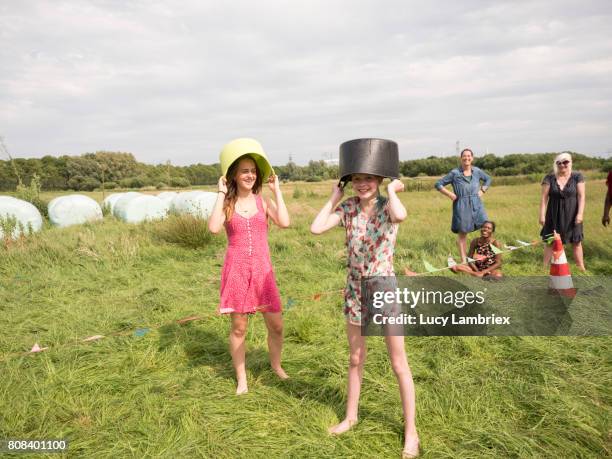 two girls holding buckets over their heads - wash bowl stock pictures, royalty-free photos & images