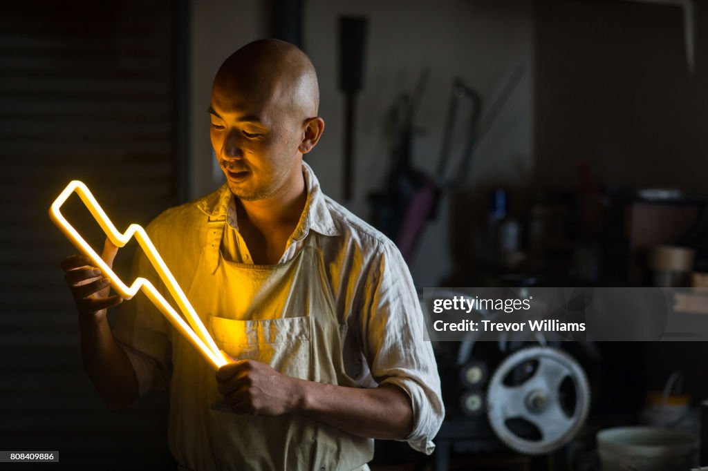 Craftsmen holding a lightning bolt shaped neon light