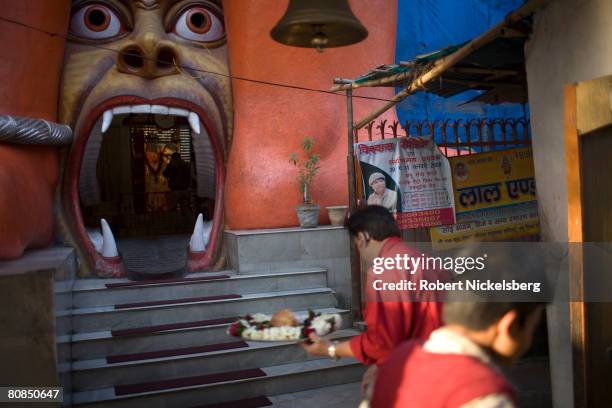 Hindu devotees carrying offerings enter a Hanuman temple below an elevated section of the New Delhi metro in the Jhandewalan district of New Delhi,...