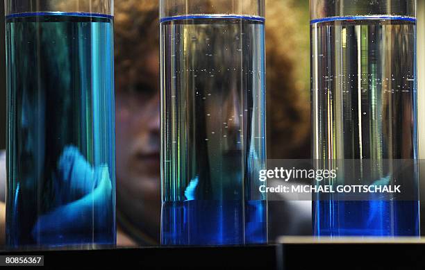 Young man inspects an exhibit of tubes filled with a liquid to demonstrate the composition of liquids in relation to thermodynamics during a preview...