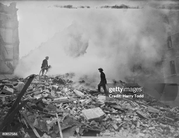 Firemen playing their hoses on the smouldering debris left after a German bombing raid on London during the Blitz, 16th October 1940.