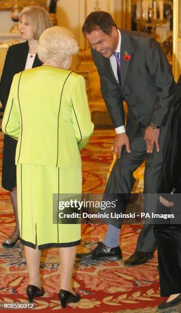 Entrepreneur Peter Jones shows Britain's Queen Elizabeth II his striped socks at the annual Civil Service Awards Reception, at Buckingham Palace,...