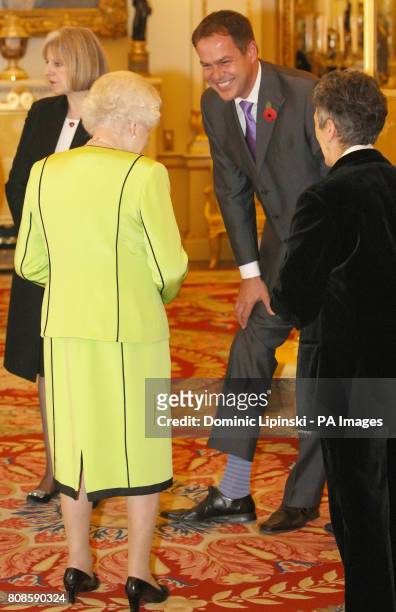 Entrepreneur Peter Jones shows Britain's Queen Elizabeth II his striped socks at the annual Civil Service Awards Reception, at Buckingham Palace,...