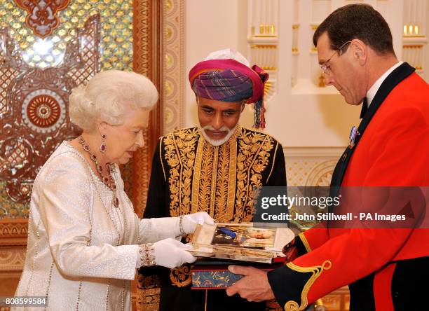 Queen Elizabeth II presents the Sultan of Oman, His Majesty Sultan Qaboos bin Said with two silver ornate framed pictures of herself and the Duke of...