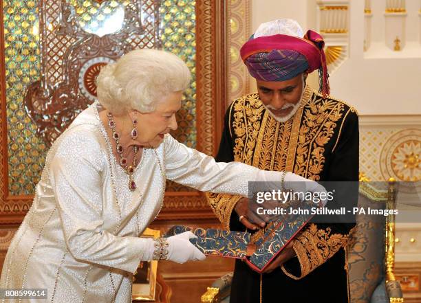 Queen Elizabeth II presents the Sultan of Oman, His Majesty Sultan Qaboos bin Said with a book , before a State Banquet at his Palace in Muscat, Oman.