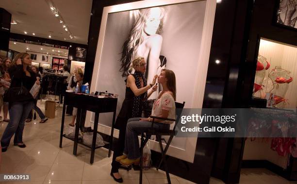 Megan Taylor, in chair, has makeup applied by Linda Hay as supermodel Marisa Miller signs autographs to celebrate the launch of Victoria's Secret...