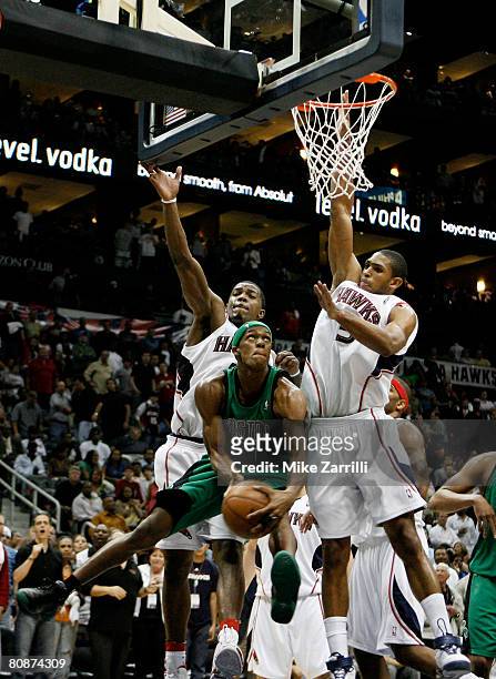 Guard Rajon Rondo of the Boston Celtics tries to score around defenders Al Horford and Joe Johnson of the Atlanta Hawks during Game Three of the...