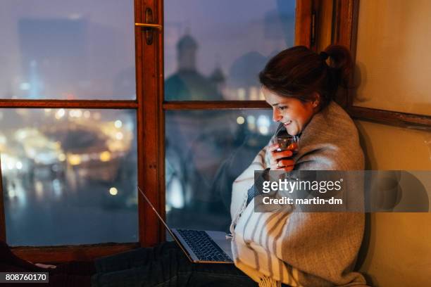 smiling woman at home watching movie on the laptop - home movie stock pictures, royalty-free photos & images