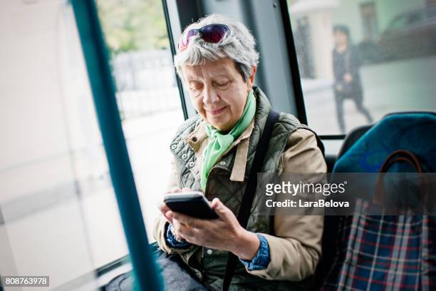 senior woman using smartphone in the bus - city 70's stock pictures, royalty-free photos & images