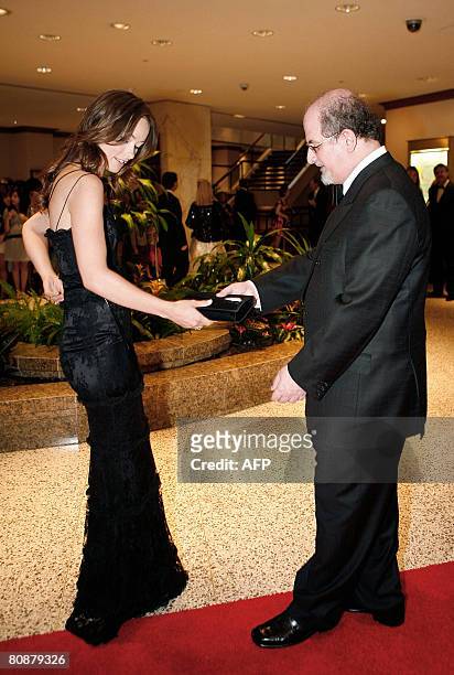 Author Salman Rushdie holds actress Olivia Wilde's bag on the red carpet as they arrive at the White House Correspondents' Association dinner on...