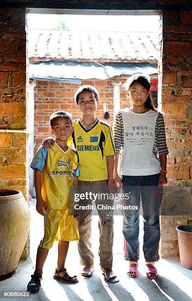 Fourteen-year-old Xu Liguan , thirteen-year-old Xu Dingping and ten-year-old Xu Dingwen, orphans from the Hebei Village of Fucheng Township, poses...