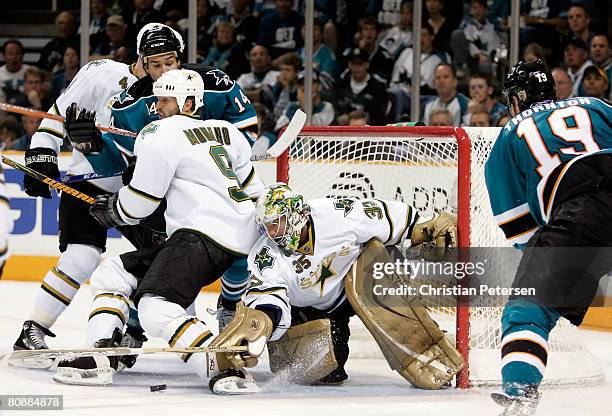 Goaltender Marty Turco of the Dallas Stars attempts to cover the puck as Mike Modano blocks out Jonathan Cheechoo of the San Jose Sharks during Game...