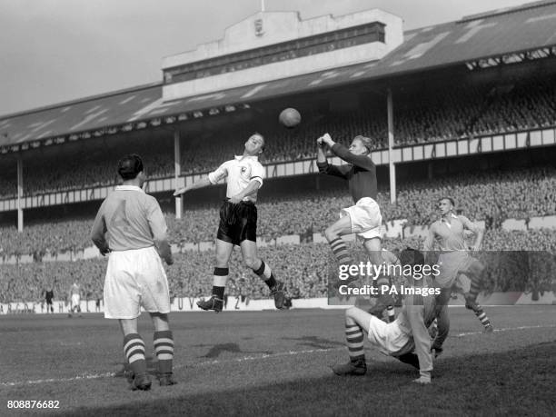 Eddie Baily, Tottenham inside left, jumps for the ball as Bert Trautmann, Manchester City goalkeeper, leaps in an attempt to beat him to the punch.