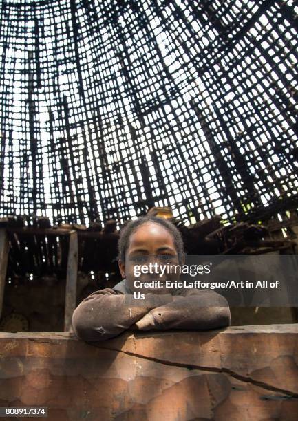 Girl under a Gurage traditional roof without thatch in renovation, Gurage Zone, Butajira, Ethiopia on June 18, 2017 in Butajira, Ethiopia.