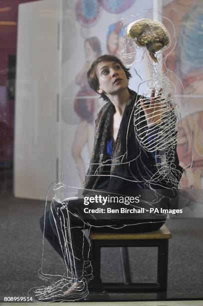 Nicole Briggs, from @Bristol science attraction, inspects a real human brain suspended in liquid with a to-scale skeleton, central nervous system and...