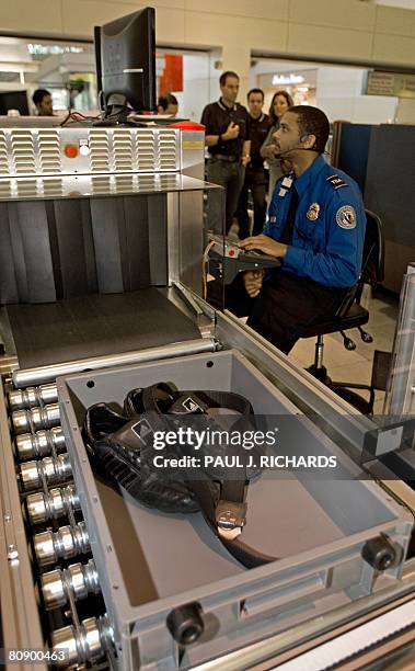 Transportation Safety Administration officer reads the X-ray of the shoes and belt that ride in a new style bin for carry-ons at the Checkpoint...