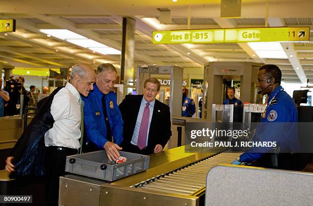 Homeland Security Secretary Michael Chertoff removes his jacket as he tries out the new carry-on system at the Checkpoint Evolution prototype at...