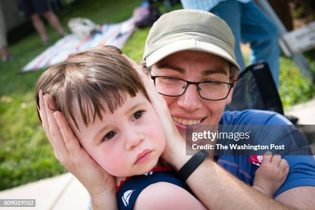 Melissa Scopilliti, of College Park, Maryland hold's the ears of her daughter, Evelyn Poling as fire engines and ambulances with sirens pass. Takoma...