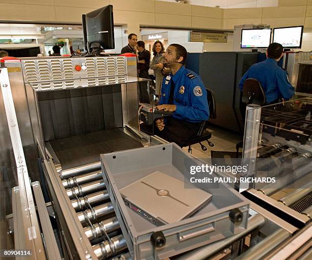 Transportation Security Administration officer reads the X-ray of a laptop computer that rides in a new style bin for carry-ons at the Checkpoint...
