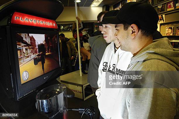 Young man plays the "Grand Theft Auto IV" video game on Playstation 3 , while a woman performs a pole dance act in the background, during the nightly...