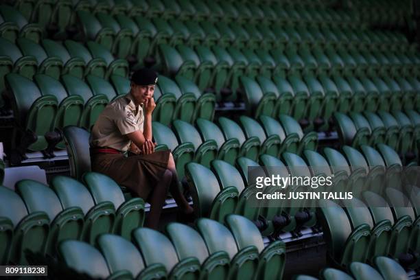 Member of the armed forces providing security sits in the seats on a court before play begins at The All England Lawn Tennis Club in Wimbledon,...