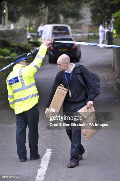 Man carries an evidence bag and a box from the scene of a double shooting in Westbury-Sub-Mendip, near Cheddar, Somerset.