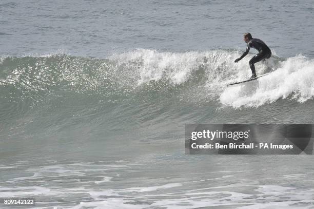 Surfer prepares to drop into a small fun wave in the warm sunshine at Woolacombe beach, North Devon.