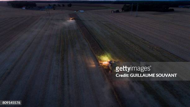 An aerial picture shows combine harvesters in action during a rape harvest on July 04, 2017 near Monthodon, central France.