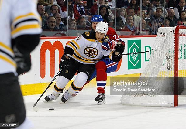Dennis Wideman of the Boston Bruins brings the puck around the net against Steve Begin of the the Montreal Canadiens during game seven of the 2008...