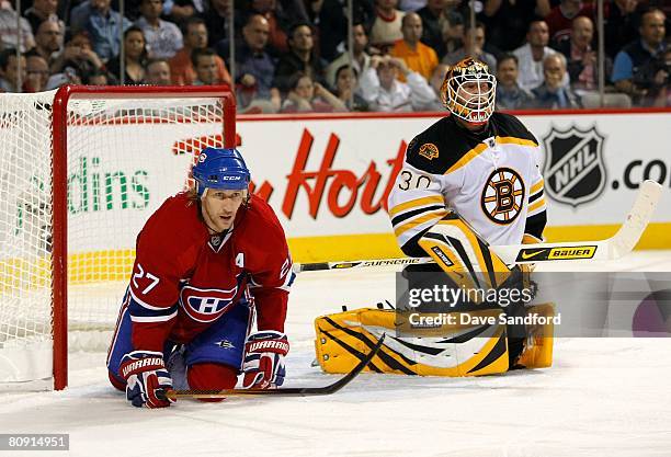 Goalkeeper Tim Thomas of the Boston Bruins defends his net as Alexei Kovalev of the Montreal Canadiens looks on from his knees in the crease area...