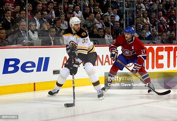 Zdeno Chara of the Boston Bruins looks to play the puck on his backhand as Alexei Kovalev of the the Montreal Canadiens pressures the play during...