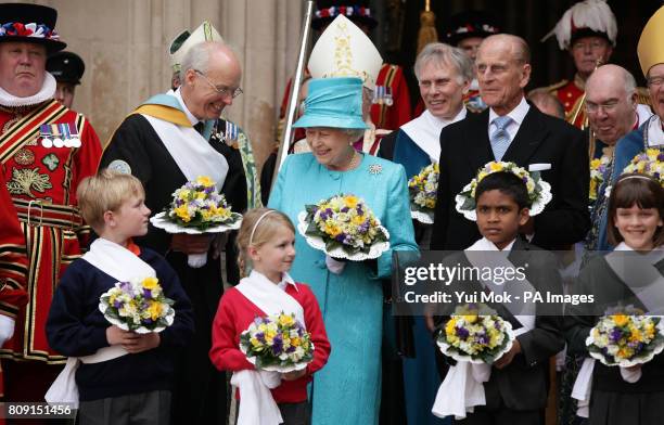 Queen Elizabeth II and the Duke of Edinburgh with children holding flowers as they leave the traditional Royal Maundy Service at Westminster Abbey on...