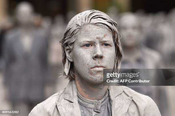 Performer smeared with clay demonstrates during the art action "1000 Gestalten" on July 5, 2017 on a street in Hamburg, northern Germany, where...