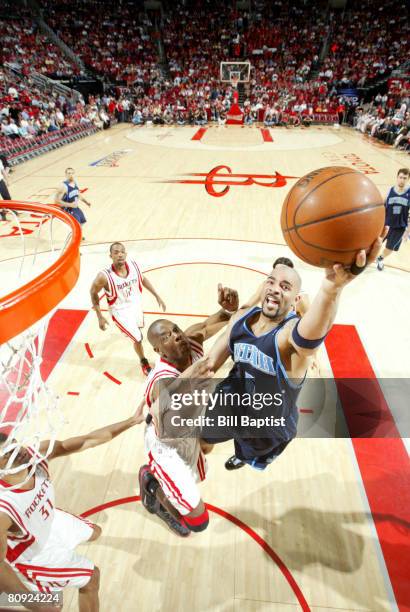 Carlos Boozer of the Utah Jazz drives to the basket as Dikembe Mutombo of the Houston Rockets tries to block the shot in Game Five of the Western...