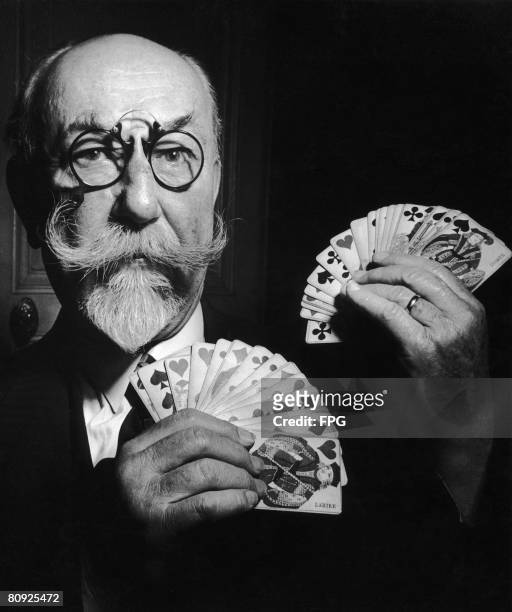 French conjuror holds up a pair of fanned-out hands of cards, circa 1935.