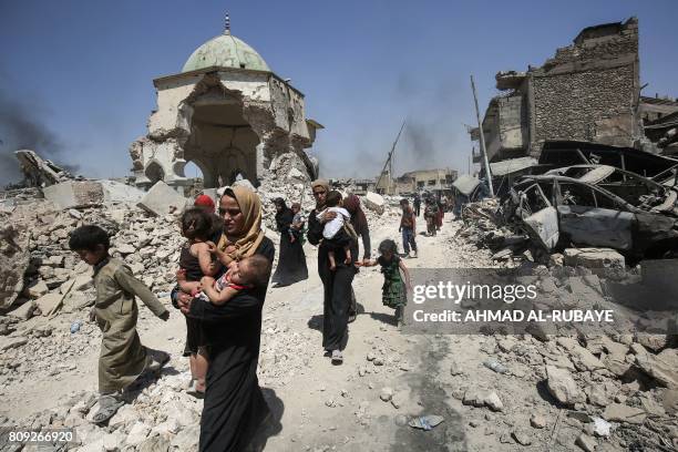 Iraqis walk by the destroyed Al-Nuri Mosque as they flee from the Old City of Mosul on July 5 during the Iraqi government forces' offensive to retake...