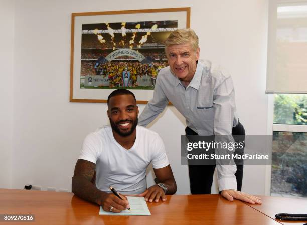 New signing Alexandre Lacazette signs his contract with Arsenal manager Arsene Wenger at London Colney on July 4, 2017 in St Albans, England.