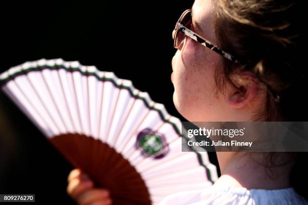 Spectators uses a fan to keep cool on day three of the Wimbledon Lawn Tennis Championships at the All England Lawn Tennis and Croquet Club on July 5,...