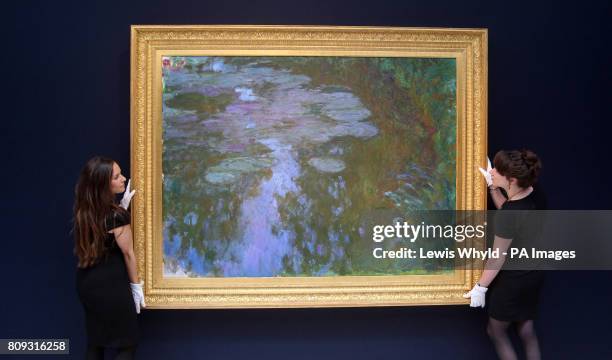 Christie's employees handle Claude Monet's 'Nympheas' or Water Lilies painting at Christie's in London, which is expected to fetch £17 000 to...