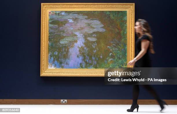 Christie's employee walks past Claude Monet's 'Nympheas' or Water Lilies painting at Christies in London, which is expected to fetch 17 000 to 24 000...