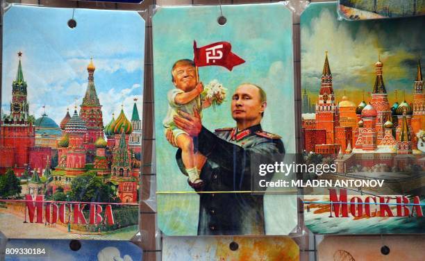 Picture taken on July 5, 2017 shows a souvenir kiosk offering among others a drawing depicting Russian President Vladimir Putin holding a baby with...