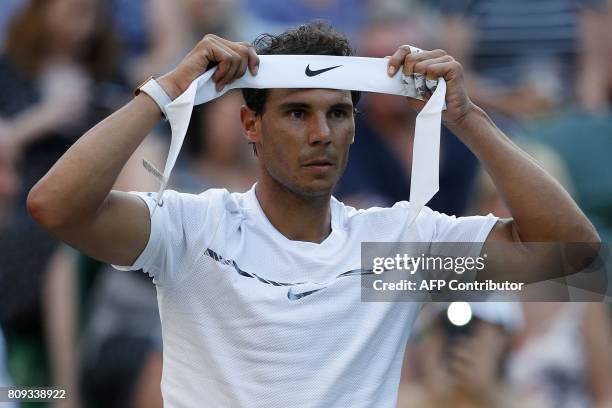 Spain's Rafael Nadal chages his head band during a break in play against US player Donald Young during their men's singles second round match on the...