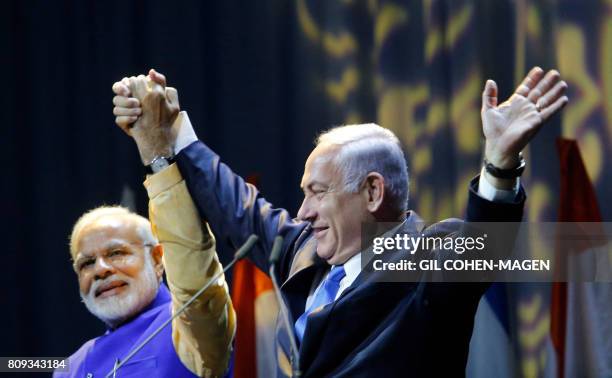 Israeli Prime Minister Benjamin Netanyahu holds hands with his Indian counterpart Narendra Modi during a meeting with Indian community at the Tel...