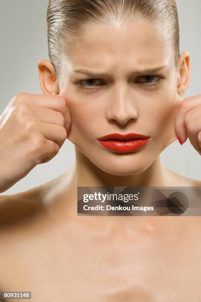 portrait of a young woman pulling her cheeks with her hands - woman cheek stock pictures, royalty-free photos & images