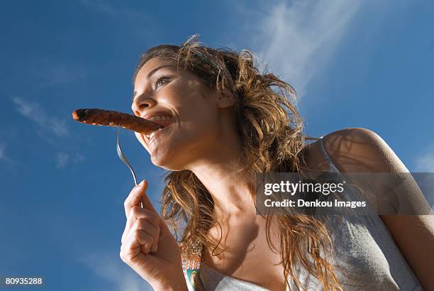 woman eating sausage - social bite stock pictures, royalty-free photos & images