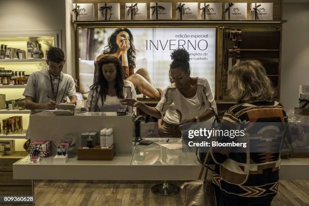 An employee assists a customer at a checkout counter in a Natura Cosmeticos SA store inside the Santos Dumont Airport in Rio de Janeiro, Brazil, on...